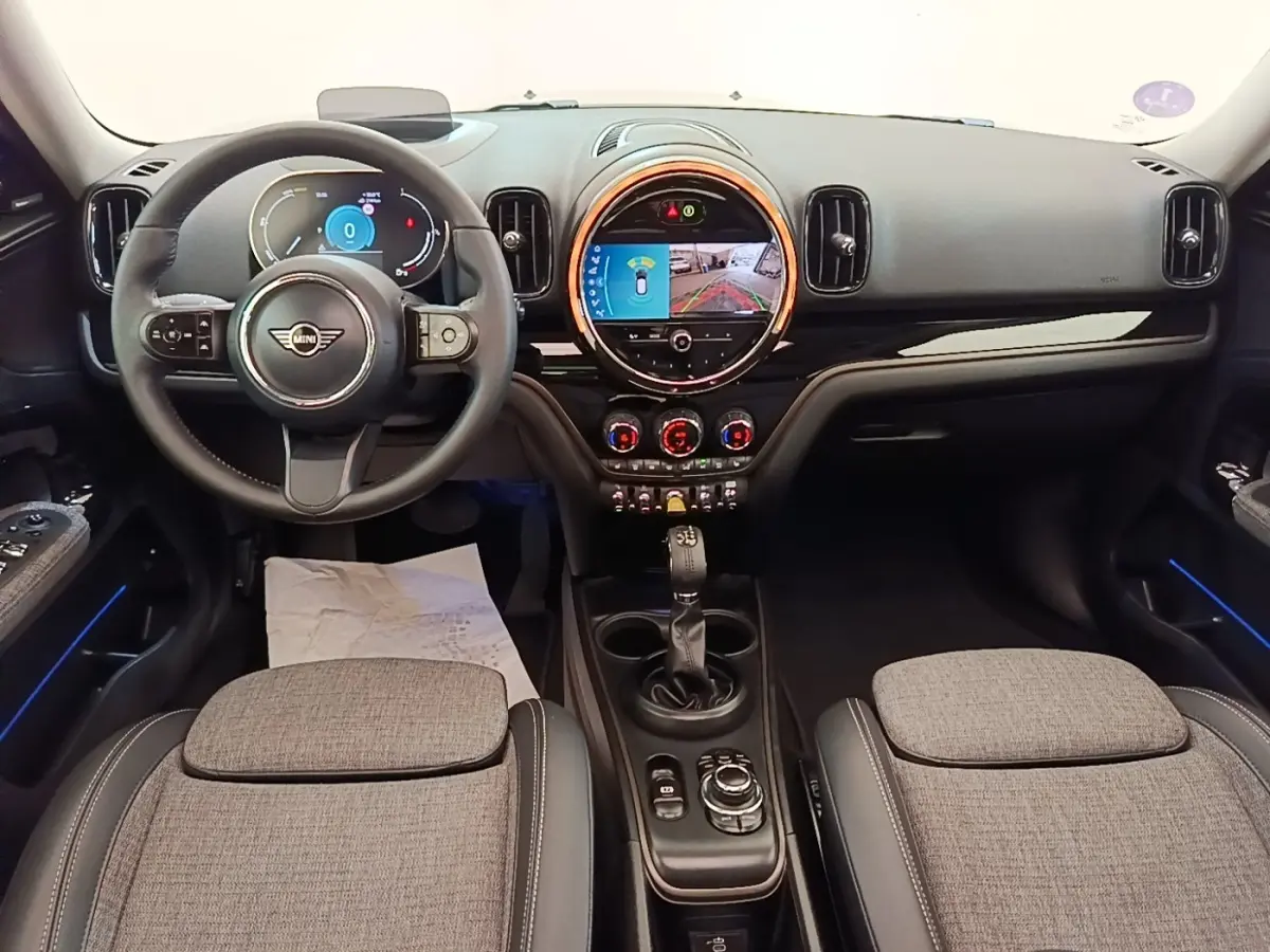 Intérieur avant du MINI Countryman 2023, vue tableau de bord et volant cuir noir avec écran tactile central lumineux.