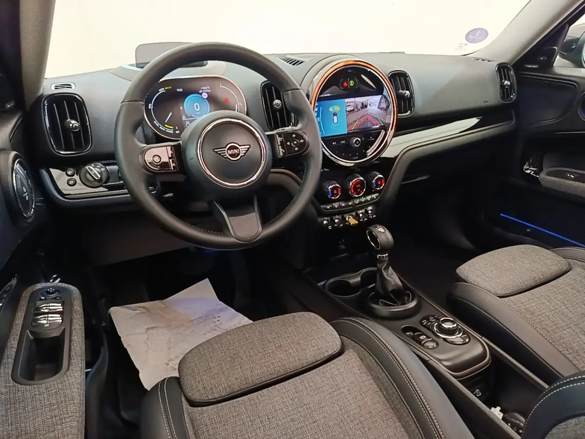 Vue intérieure avant du MINI Countryman Cooper SE avec volant cuir noir et écran tactile central lumineux.