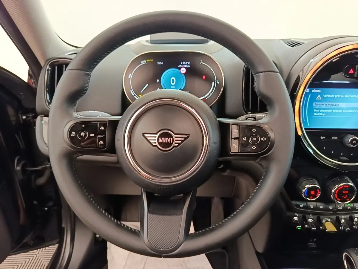 Vue intérieure centrée sur le volant cuir noir multifonctions du MINI Countryman 2023 avec tableau de bord numérique.