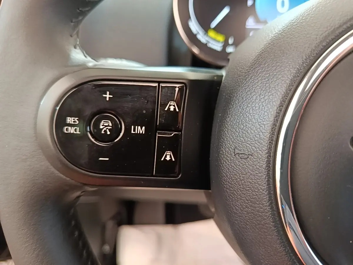 Gros plan sur les commandes de régulateur de vitesse au volant cuir noir du MINI Countryman hybride 2023.