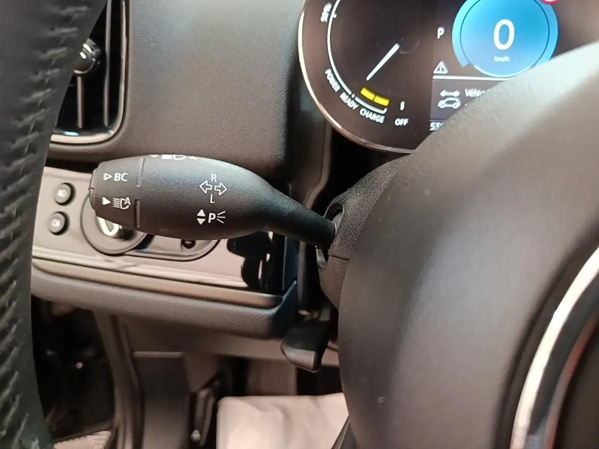 Gros plan sur la manette de clignotant noire à gauche du volant cuir dans l’habitacle du MINI Countryman noir 2023.