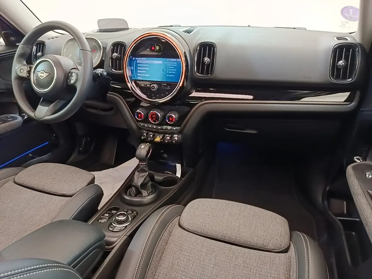 Vue intérieure avant droite du tableau de bord noir et gris du MINI Countryman Cooper SE avec écran tactile circulaire et volant cuir.