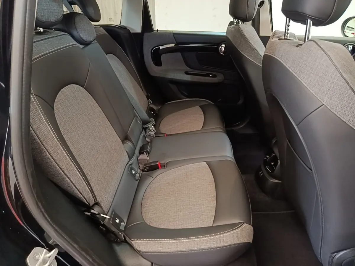 Vue intérieure côté gauche montrant la banquette arrière bi-matière tissu et cuir du MINI Countryman noir 2023.