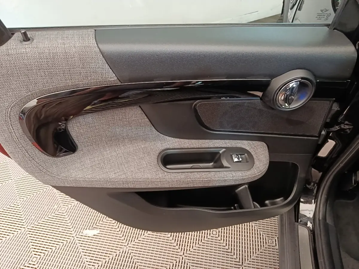 Gros plan sur la porte intérieure côté gauche de la MINI Countryman noire, avec habillage tissu gris et poignée noire brillante.
