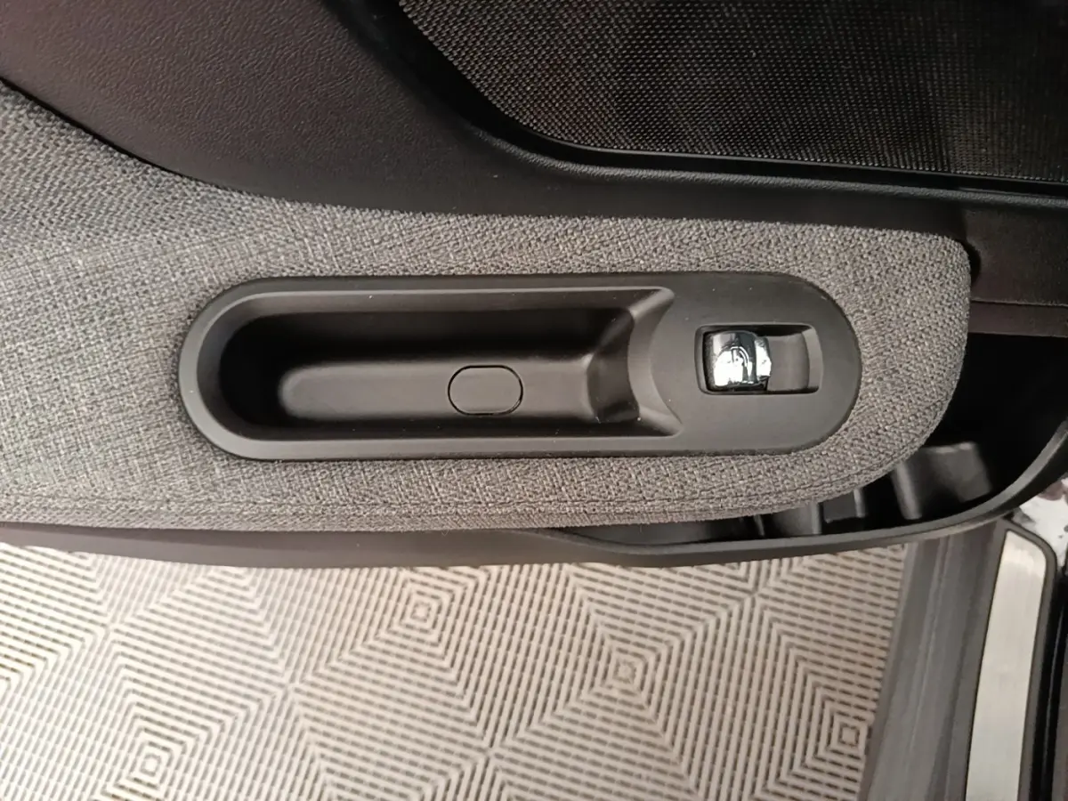Poignée intérieure de porte côté gauche du MINI Countryman noir, avec revêtement tissu gris et bouton chromé.