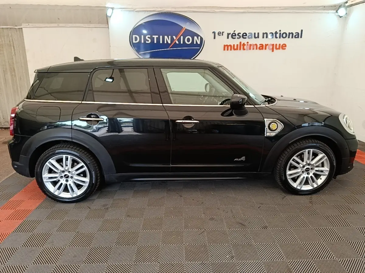 Profil côté gauche d'un MINI COUNTRYMAN Cooper SE hybride rechargeable noir, avec jantes argentées et logo ALL4 visible.