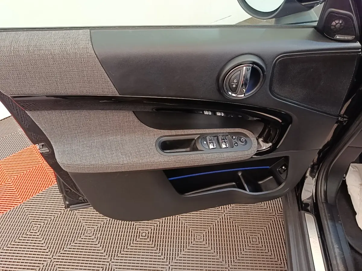 Vue rapprochée de la porte avant gauche noire du MINI COUNTRYMAN 2023 avec garniture tissu gris et commandes électriques.
