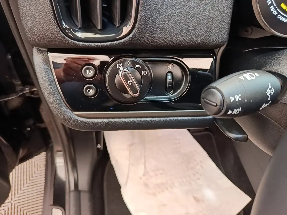 Gros plan sur les commandes d’éclairage et le commodo à gauche du volant dans l’habitacle noir du MINI Countryman 2023.