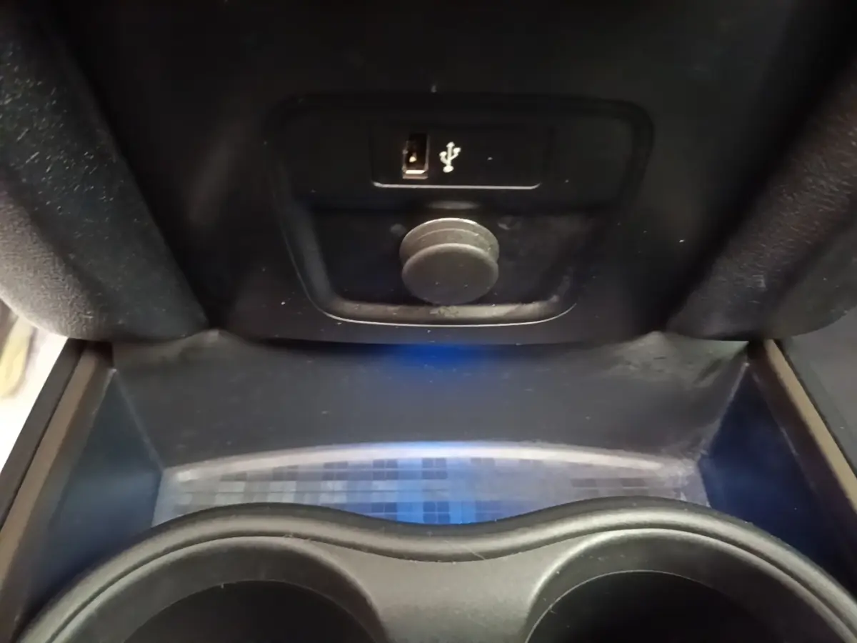 Gros plan sur la console centrale noire du MINI Countryman avec prise USB et prise 12V visibles.