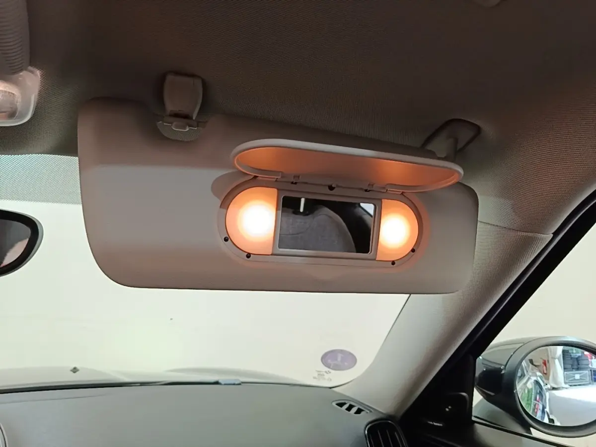 Détail du miroir de courtoisie éclairé sur le pare-soleil côté conducteur d'un MINI Countryman noir 2023 hybride rechargeable.