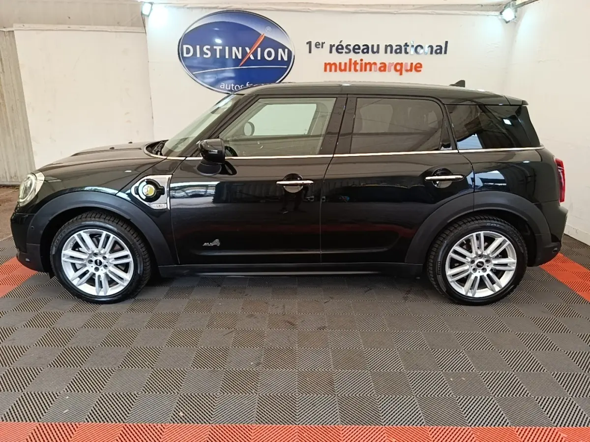Profil côté gauche d’un MINI Countryman Cooper SE noir hybride rechargeable, avec jantes argentées et prise de charge visible.