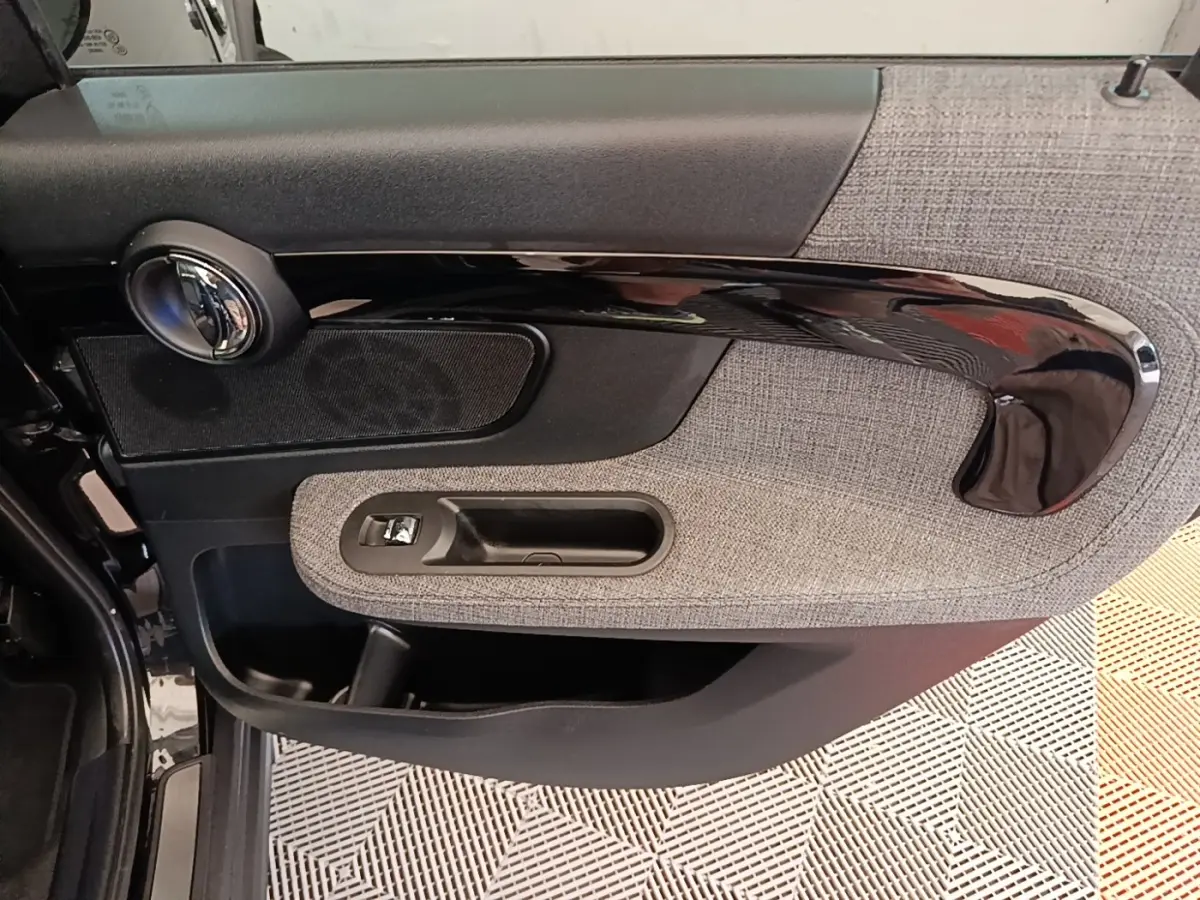 Détail de la porte avant gauche du MINI Countryman noir 2023 avec habillage tissu gris et poignée noire brillante.