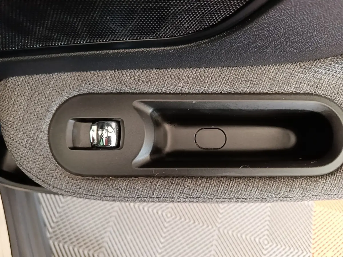Gros plan sur la poignée intérieure noire et tissu gris clair de la porte côté conducteur du MINI Countryman noir 2023.