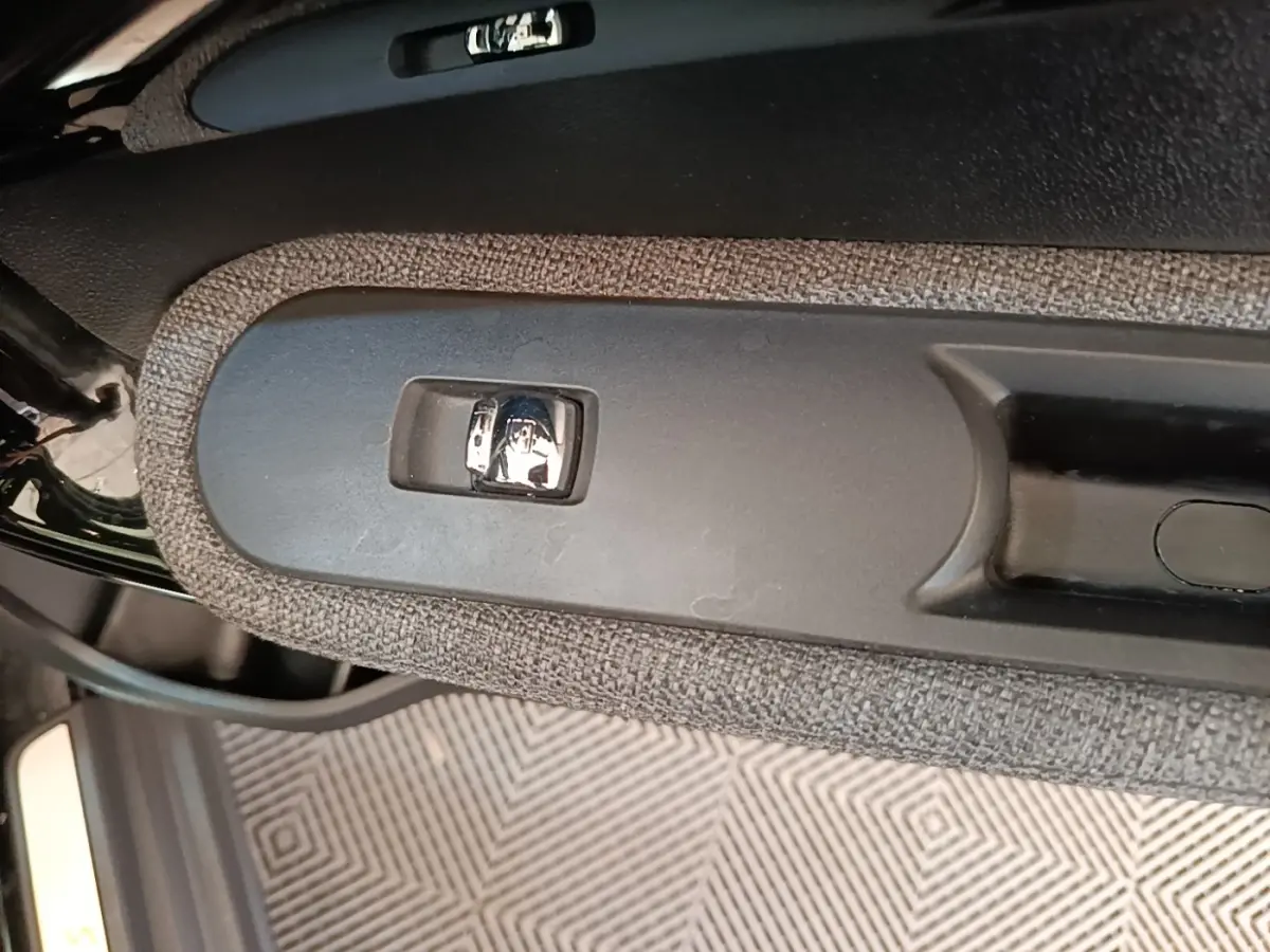 Gros plan sur la poignée intérieure de porte côté gauche du MINI Countryman noir, avec bouton de verrouillage chrome.