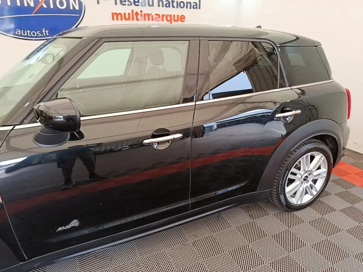 Vue latérale droite d'une MINI Countryman noire avec jantes argentées et rétroviseurs noirs brillants.