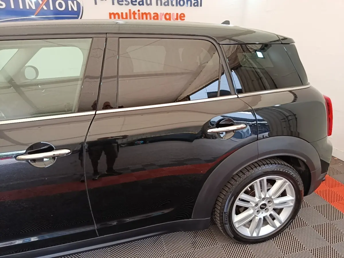 Vue de profil côté droit d'un MINI Countryman noir avec jantes alliage et poignées chromées.