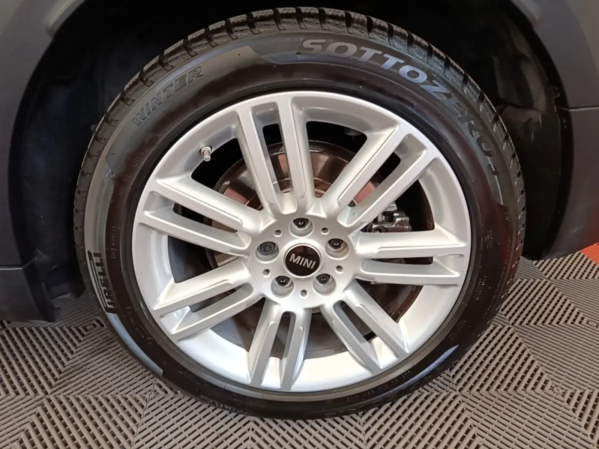Gros plan sur la roue avant gauche du MINI Countryman noir, jante alliage argentée et pneu hiver Pirelli.