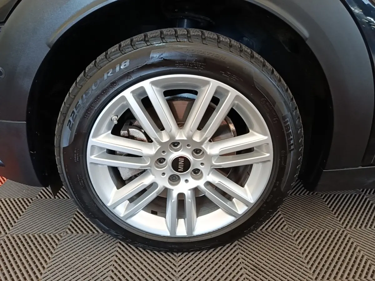 Gros plan sur la roue avant droite argentée du MINI Countryman noir 2023, mettant en valeur la jante et le pneu Pirelli.
