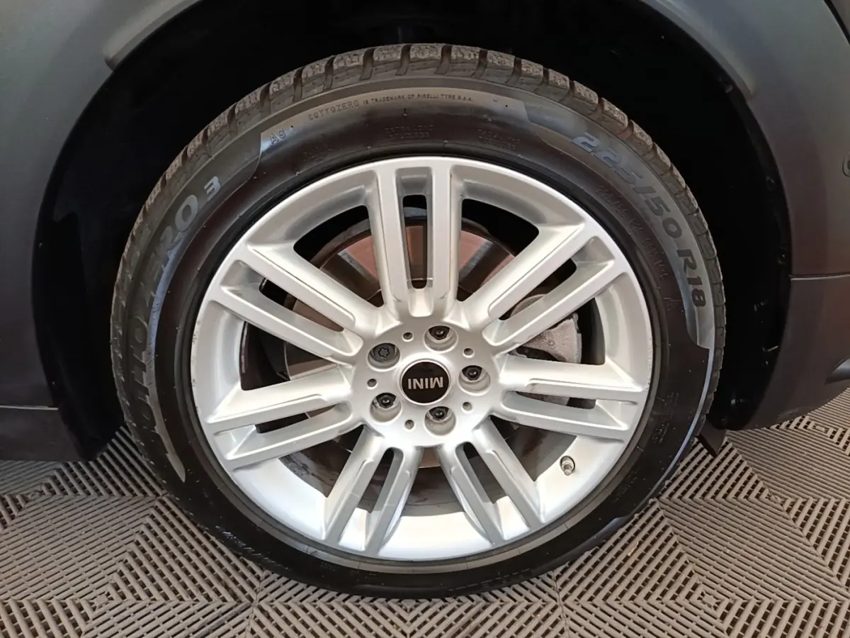 Gros plan sur la roue avant droite avec jante argentée du MINI Countryman noir hybride rechargeable 2023.
