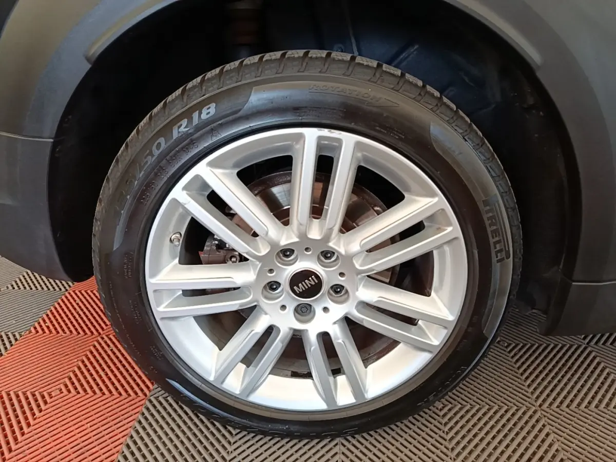 Gros plan sur la roue avant droite du MINI Countryman noir, mettant en valeur la jante alliage argentée et le pneu Pirelli.