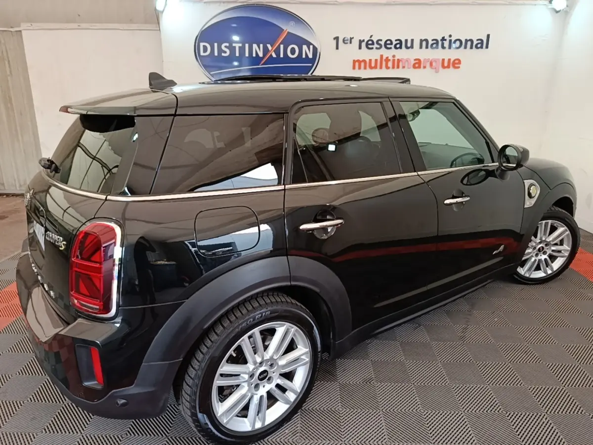Vue 3/4 arrière droite d'une MINI Countryman noire avec jantes argentées dans un showroom intérieur.