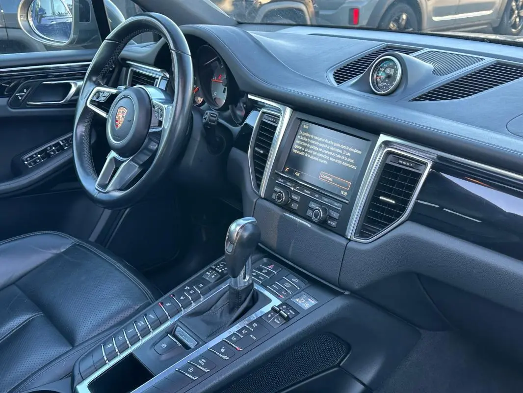 Intérieur noir du Porsche Macan Diesel 2015 vu côté conducteur, avec volant cuir multifonctions et console centrale.