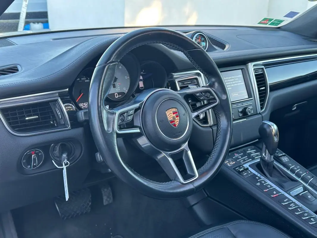 Intérieur noir du Porsche Macan 2015 vu côté conducteur, volant cuir multifonctions et console centrale avec levier de vitesse.