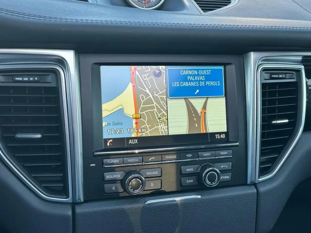 Vue rapprochée de l’écran de navigation central du tableau de bord du Porsche Macan gris foncé de 2015.