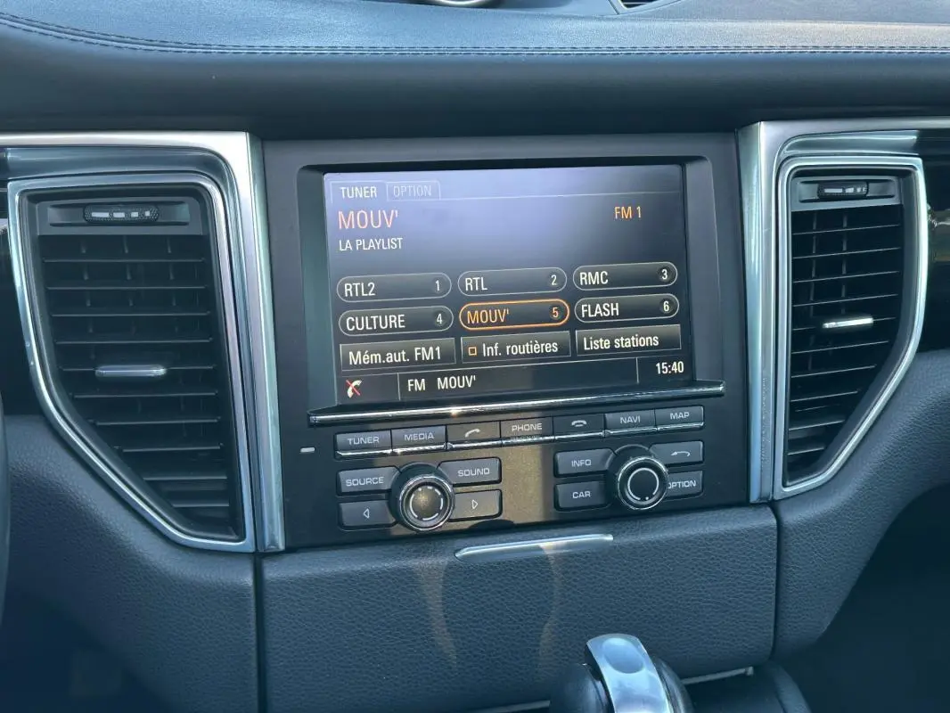 Vue rapprochée de la console centrale du Porsche Macan 2015 avec écran multimédia et commandes intégrées.
