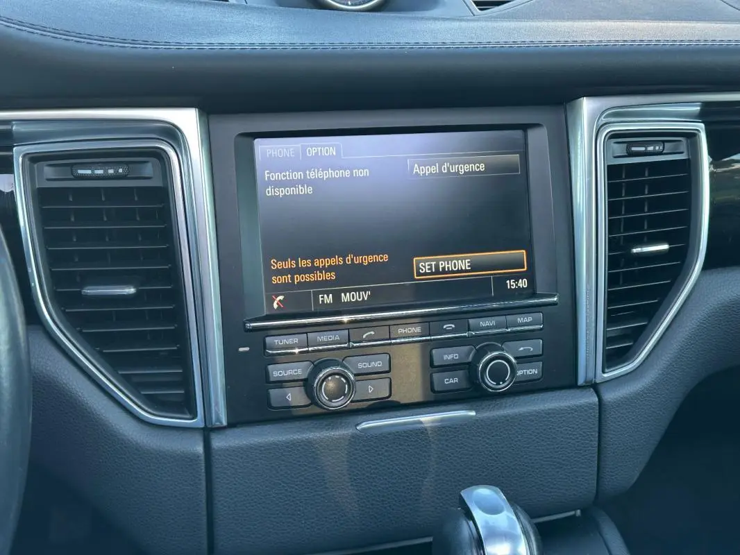 Vue rapprochée de la console centrale du Porsche Macan gris foncé, affichage multimédia et commandes intégrées.