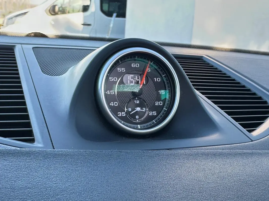 Gros plan sur l'horloge centrale du tableau de bord du Porsche Macan gris foncé de 2015.