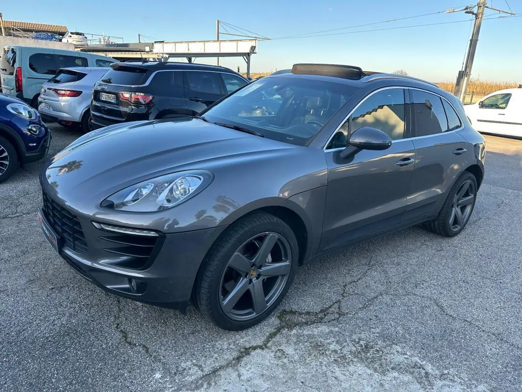 Porsche Macan gris foncé vue 3/4 avant droit, jantes 18 pouces, vitres teintées et toit panoramique visible.