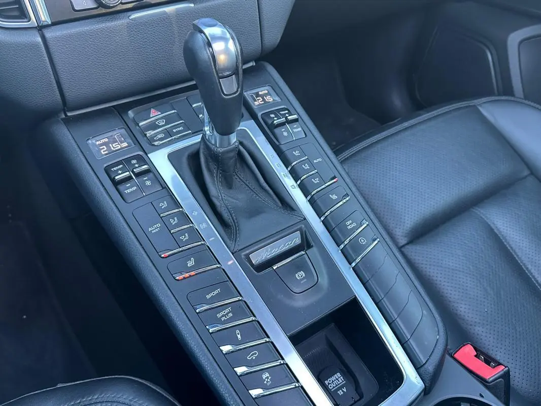 Vue rapprochée de la console centrale cuir noire du Porsche Macan 2015 avec levier de vitesse et commandes multiples.