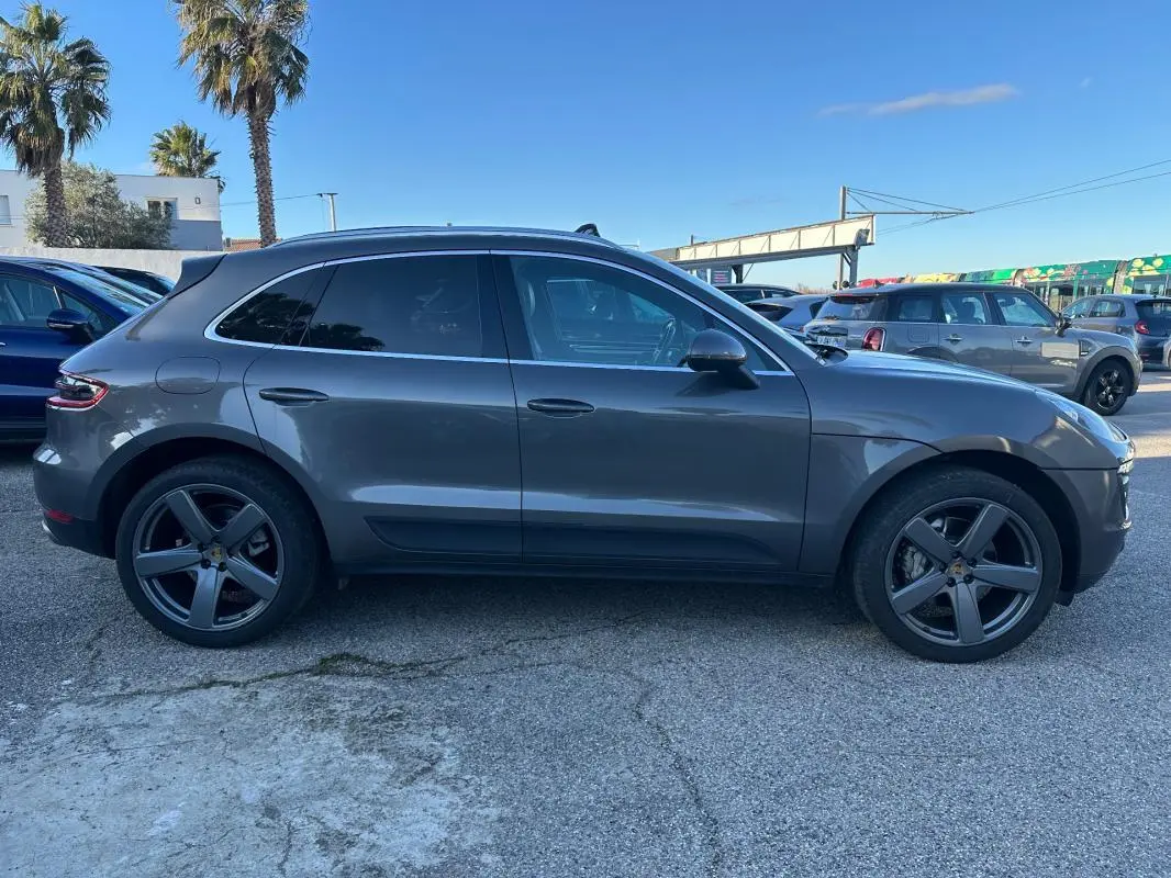 Vue de profil côté gauche d'un Porsche Macan gris foncé 2015 avec jantes 18 pouces et vitres teintées.