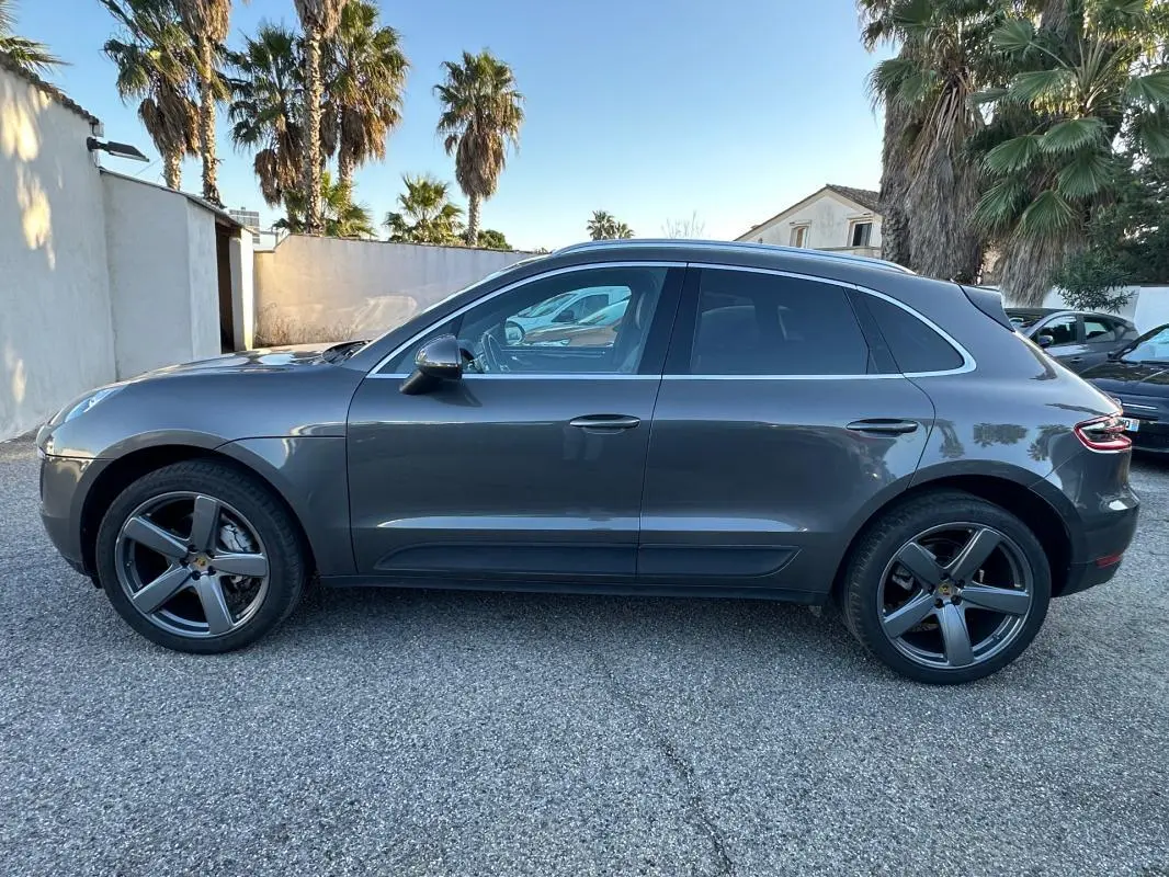 Vue latérale droite d'un Porsche Macan gris foncé avec jantes 18 pouces et vitres teintées, stationné en extérieur.
