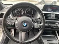 Intérieur d'une BMW Série 1 114d M Sport 2018, vue centrée sur le volant multifonction et le tableau de bord numérique.