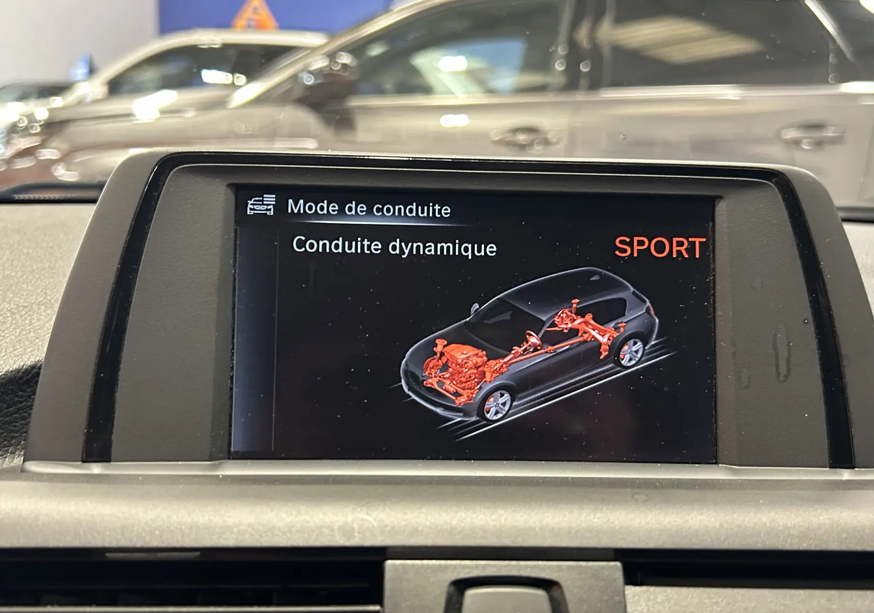Écran central montrant le mode de conduite dynamique SPORT avec schéma technique en rouge d'une BMW Série 1 gris.