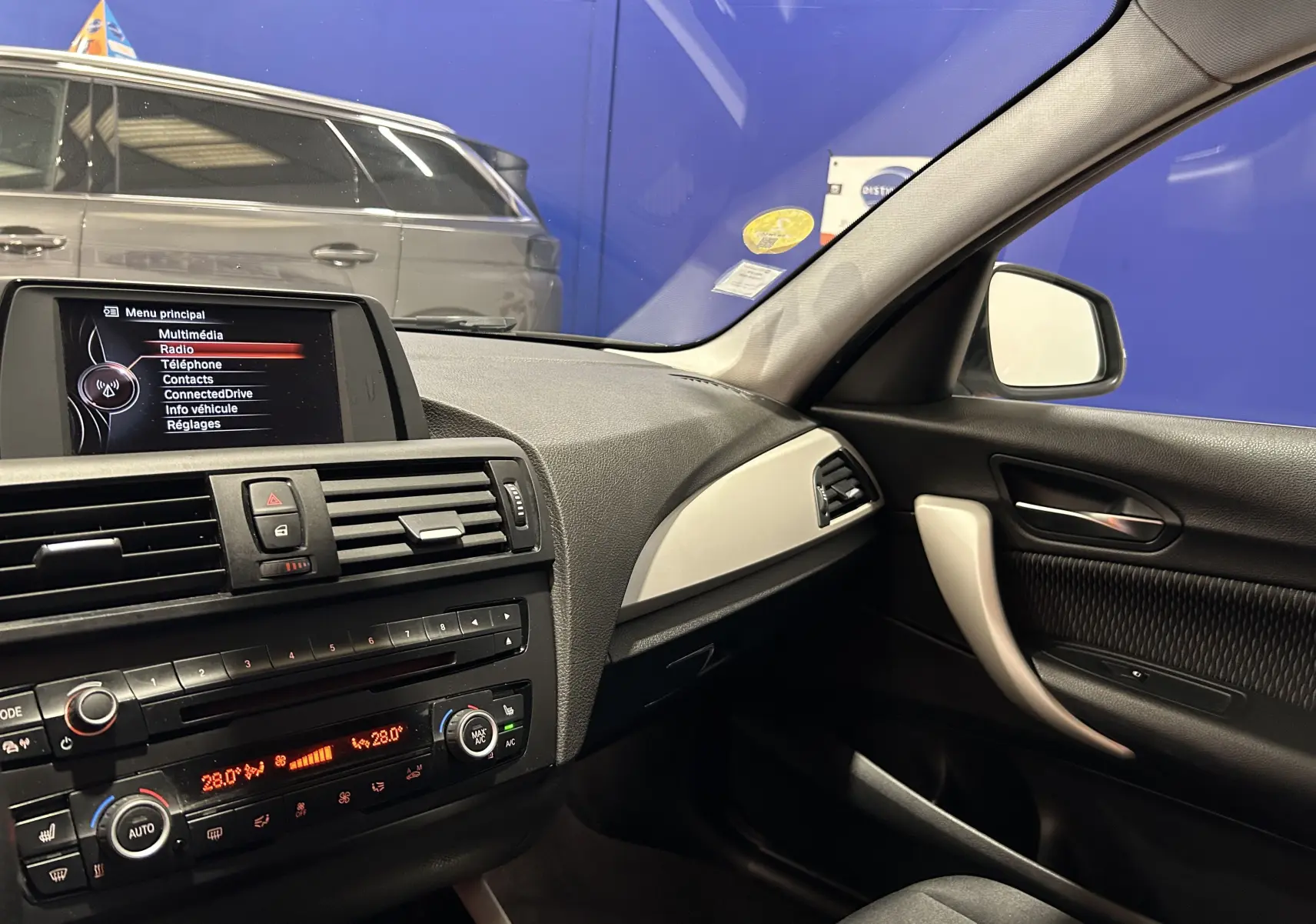 Intérieur de BMW Série 1 16d 2014, vue côté passager montrant tableau de bord et console centrale noire et grise.