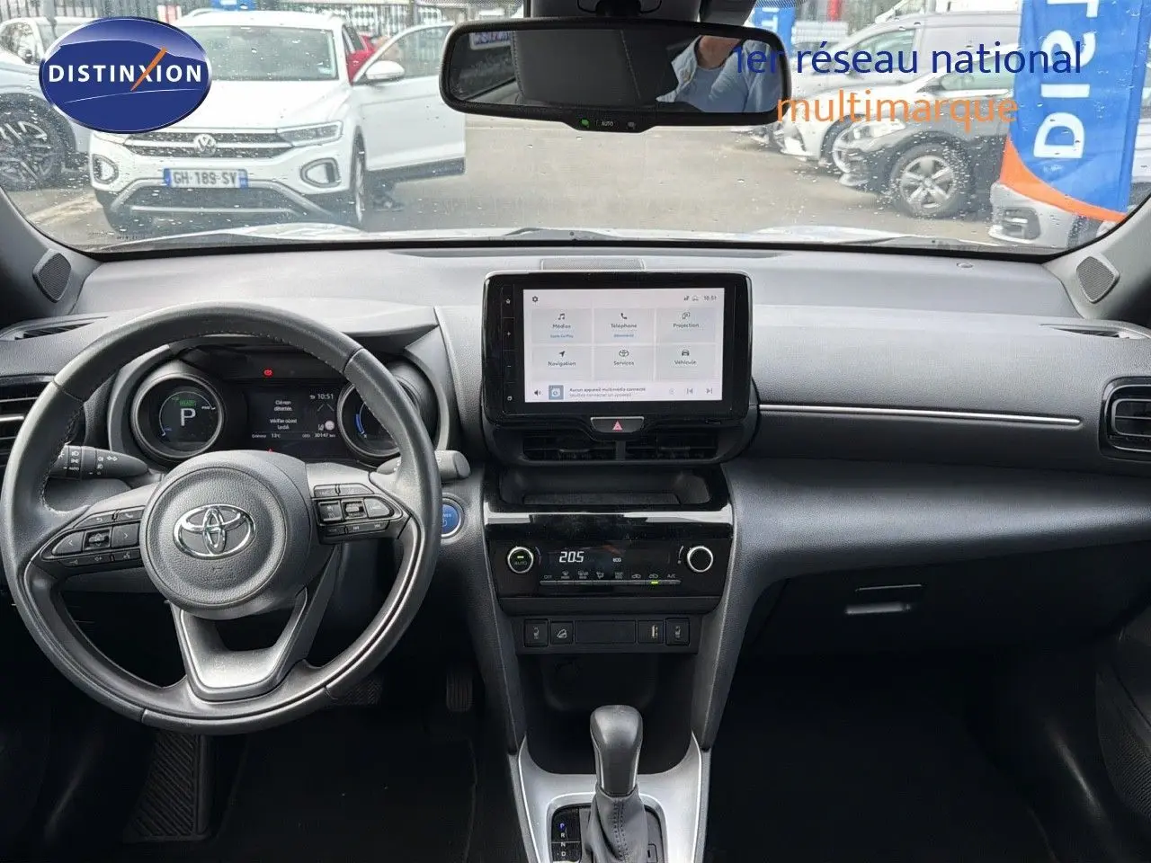 Vue intérieure du tableau de bord noir de la Toyota Yaris Cross 116h Design AWD-i avec écran tactile central et volant multifonction.