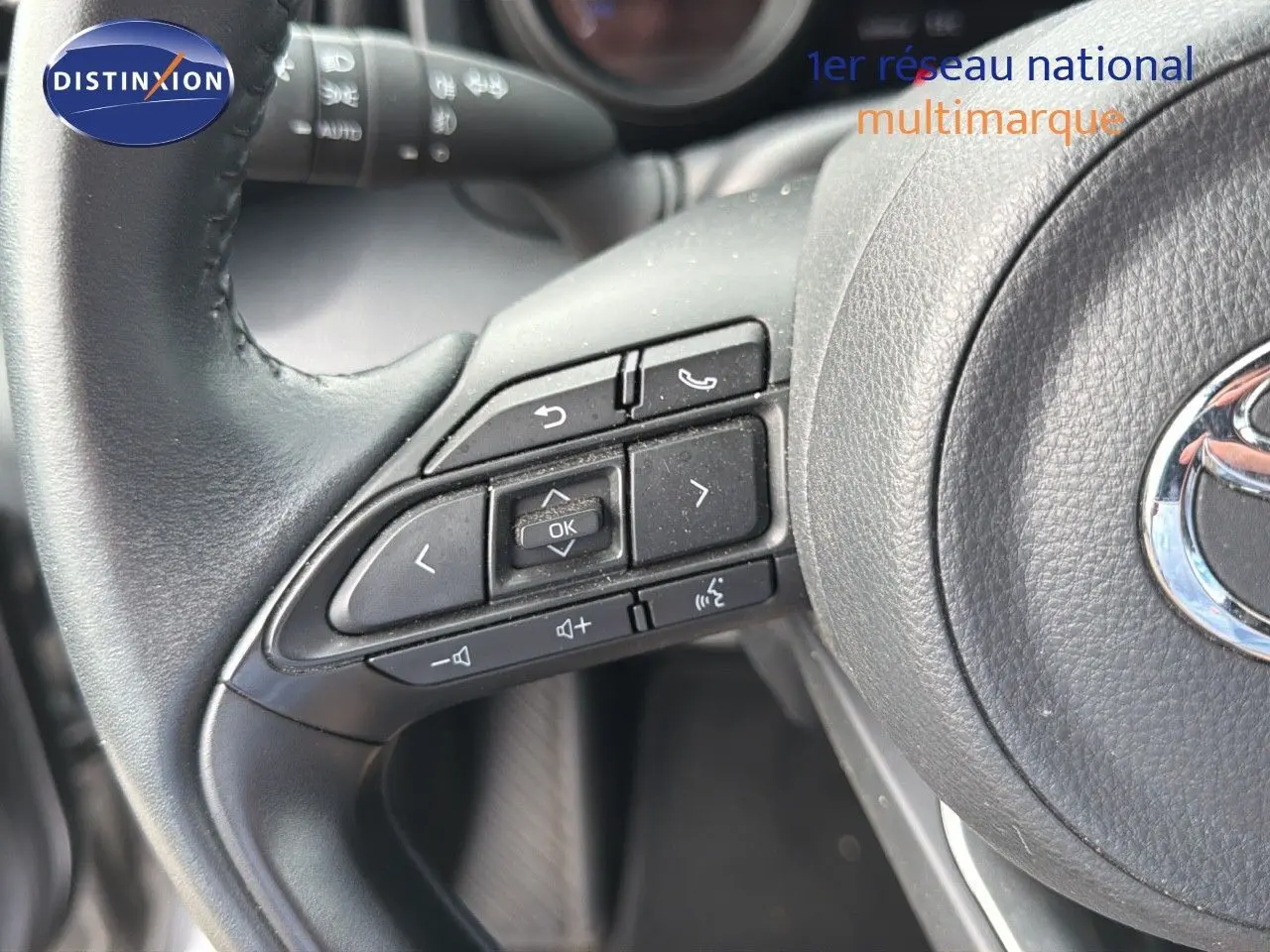 Gros plan sur les commandes au volant noir d'une Toyota Yaris Cross 116h Design AWD-i 2023.