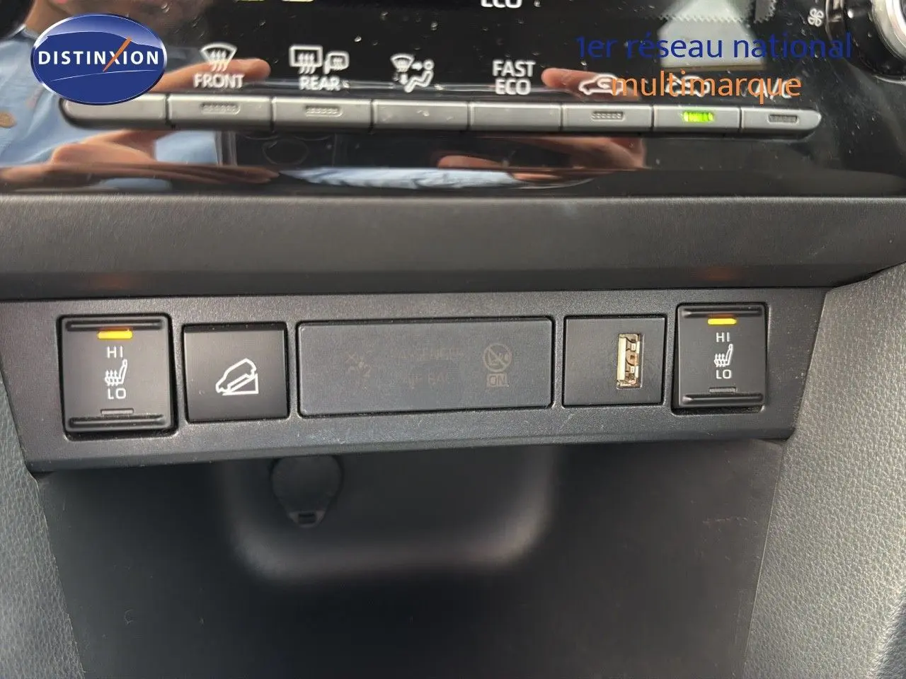 Vue rapprochée des commandes de sièges chauffants et prises USB sur la console centrale d'une Toyota Yaris Cross gris minéral.