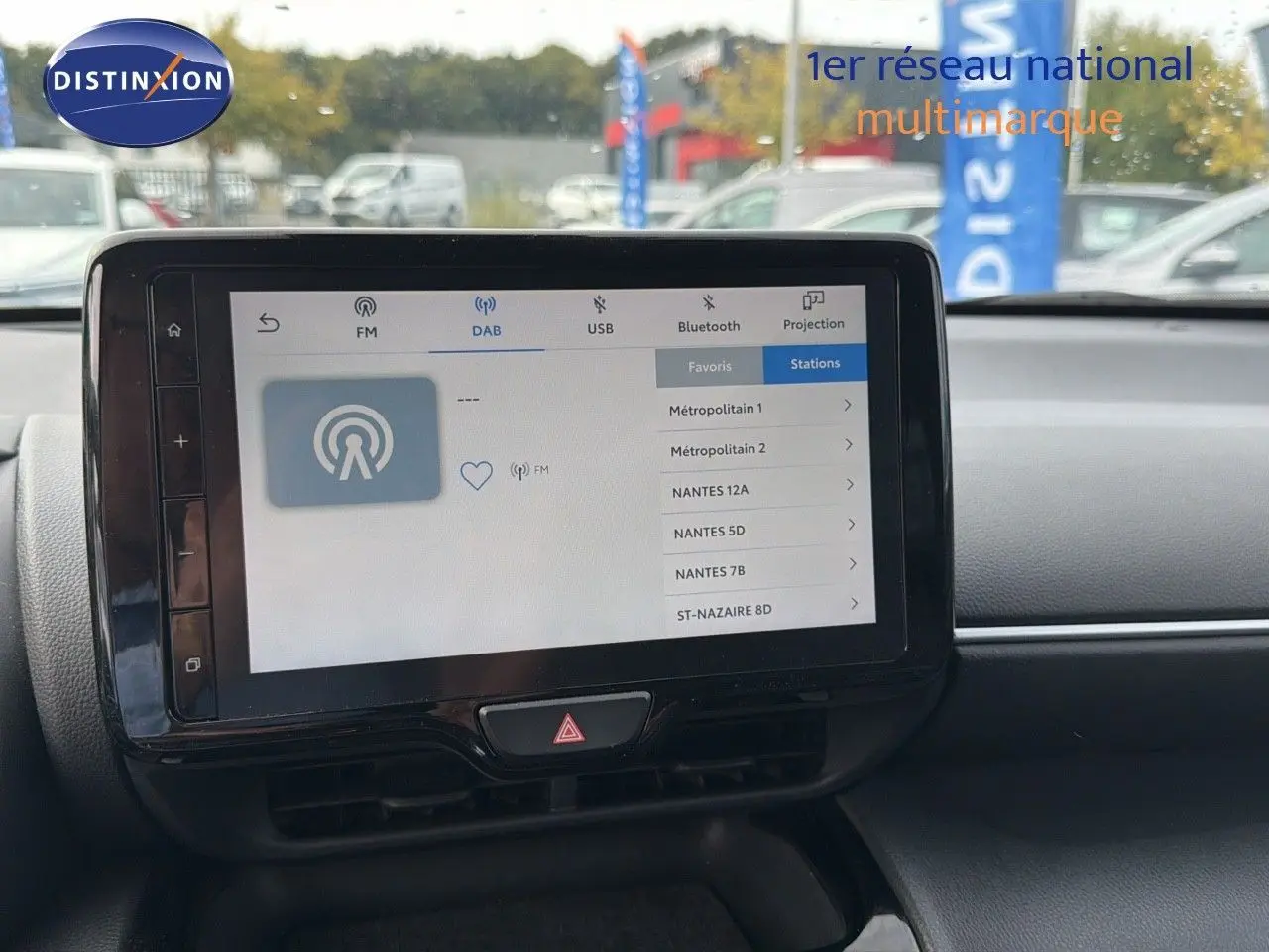 Écran tactile central du Toyota Yaris Cross gris minéral, affichant les options radio DAB en extérieur jour.