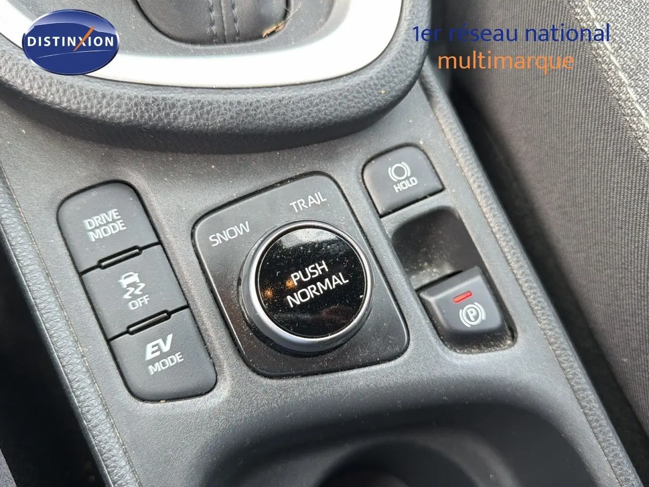 Gros plan sur la console centrale de la Toyota Yaris Cross 116h Design AWD-i avec commandes de modes de conduite en noir.