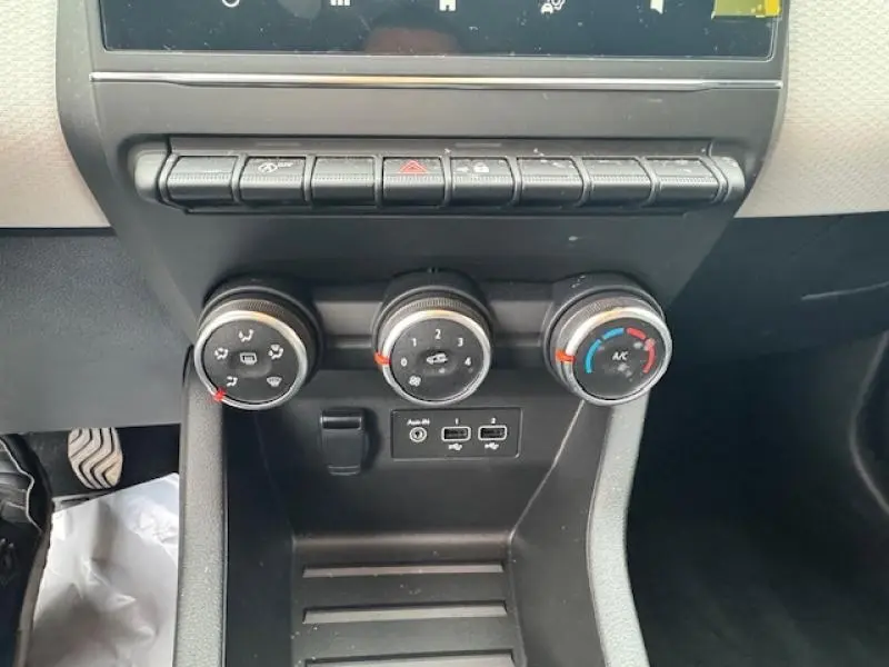 Vue rapprochée des commandes de climatisation et des ports USB sur la console centrale noire de la Renault Clio Blanc Glacier 2023.