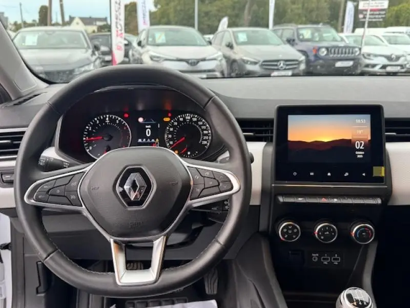 Vue intérieure centrée sur le volant multifonction et l'écran tactile de la Renault Clio Blanc Glacier 2023.