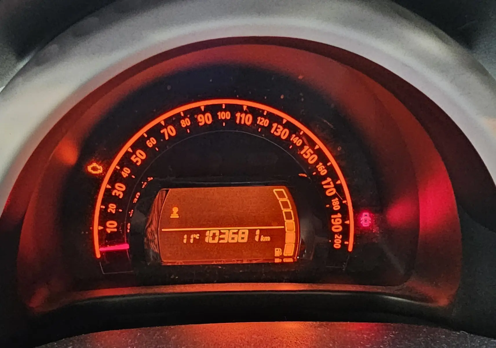 Compteur de vitesse éclairé en orange sur Renault Twingo III gris lunaire, affichant 103681 km et température extérieure 11°C.