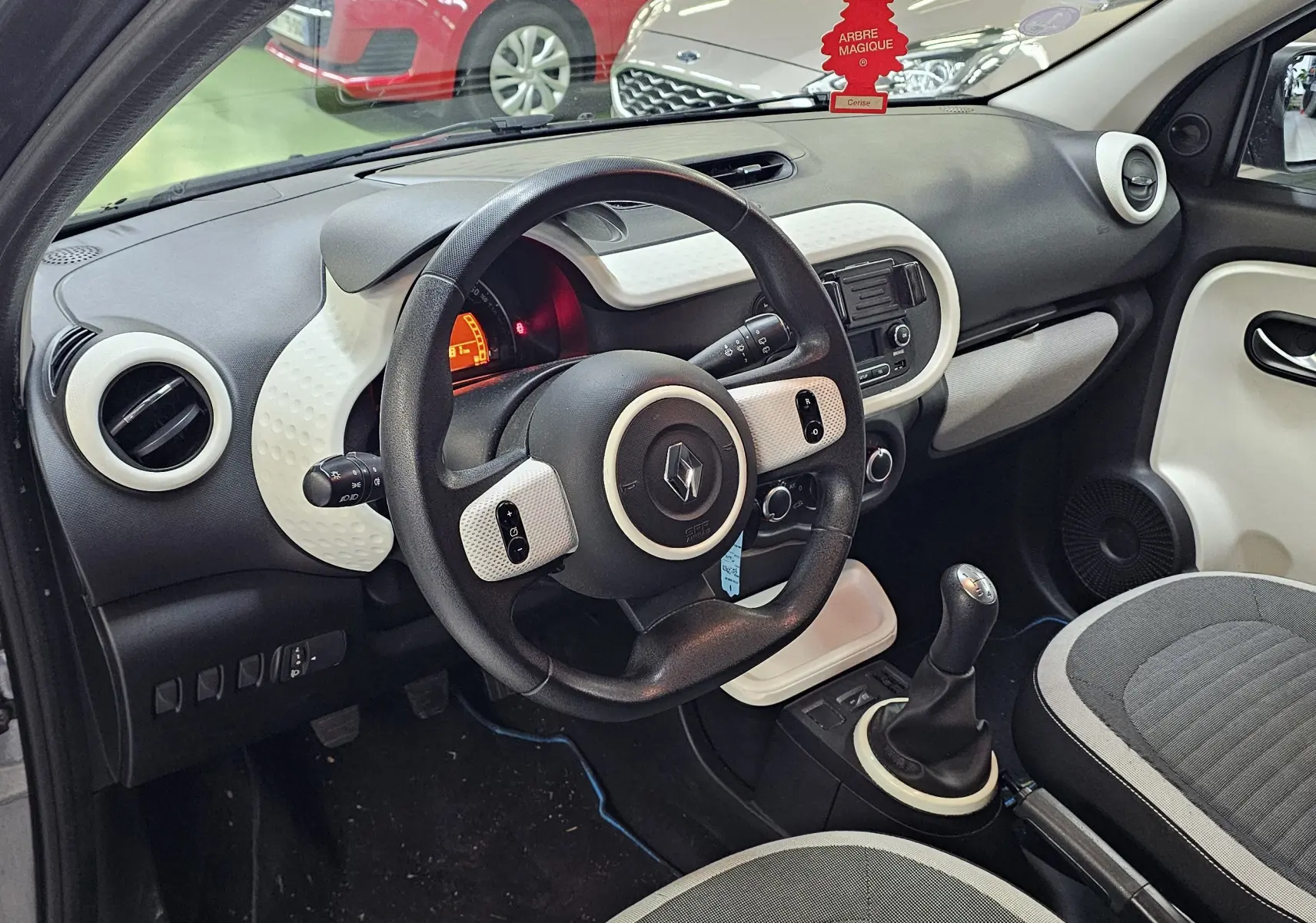 Vue intérieure côté conducteur de la Renault Twingo III gris lunaire 2018, volant et tableau de bord avec console centrale.
