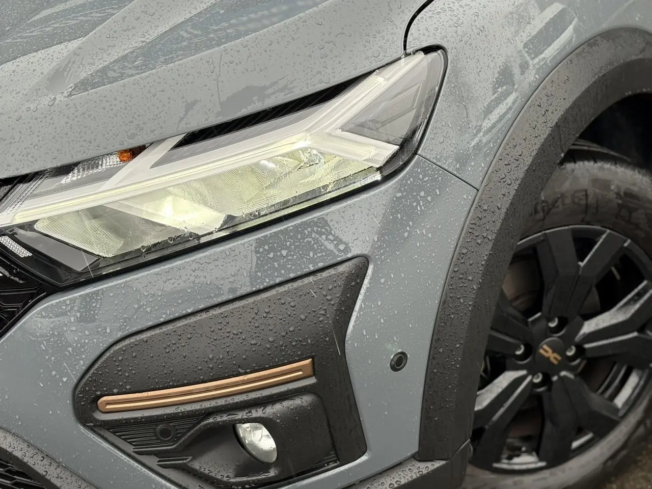 Gros plan sur l'avant droit gris urbain du Dacia Jogger 1.6 Hybrid 140 avec feux LED et jante noire Mahalia.