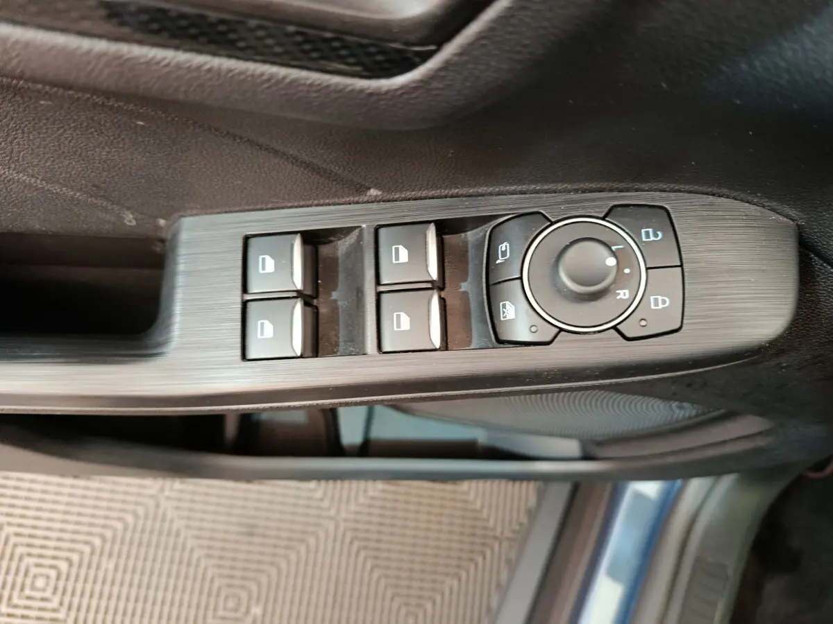 Vue rapprochée des commandes de lève-vitres et rétroviseurs côté conducteur du Ford Kuga bleu 2024 St Line.