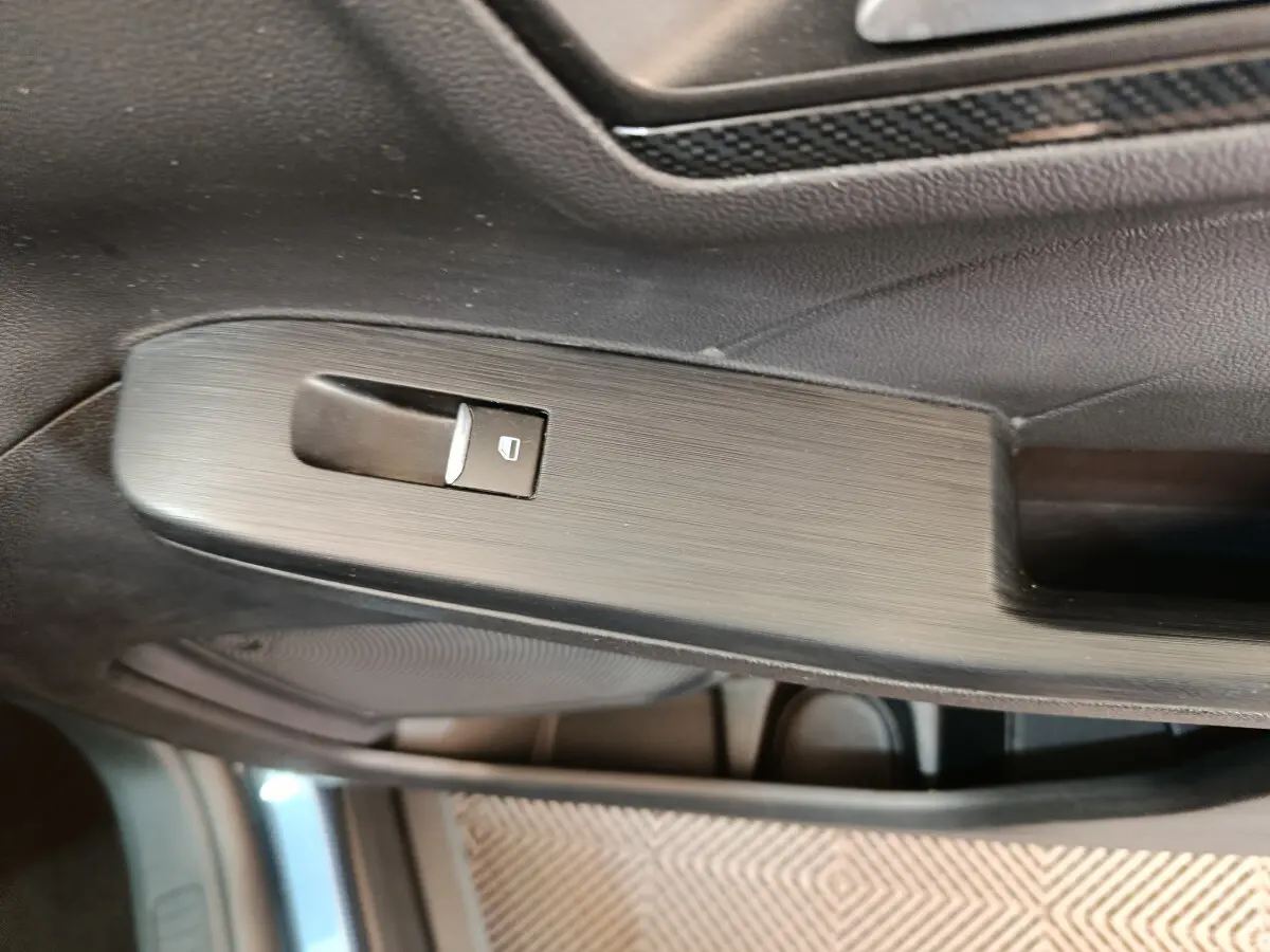 Détail de la commande de lève-vitre côté gauche intérieur d’un Ford Kuga bleu 2024 finition St Line.